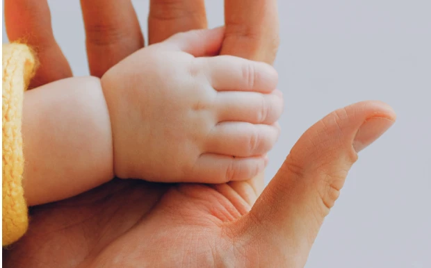Mão de um bebê segurando o dedo de um adulto
